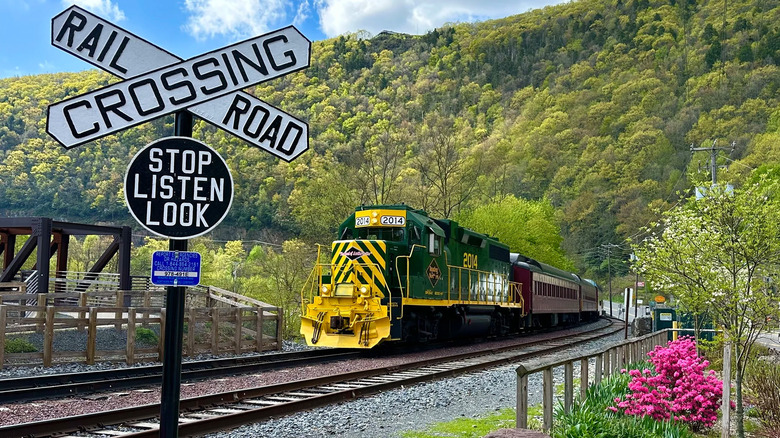 A train riding on tracks near a hill