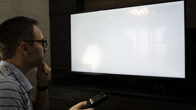 Man watching television, in a thinking posture.