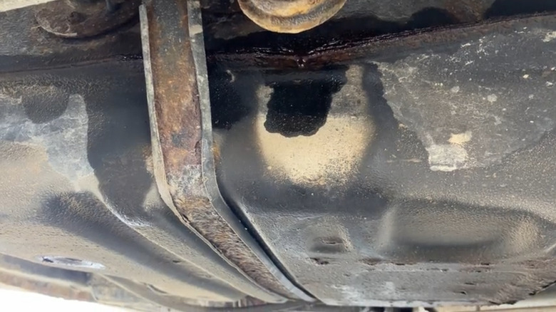 A close-up of a car's gas tank actively leaking fuel.