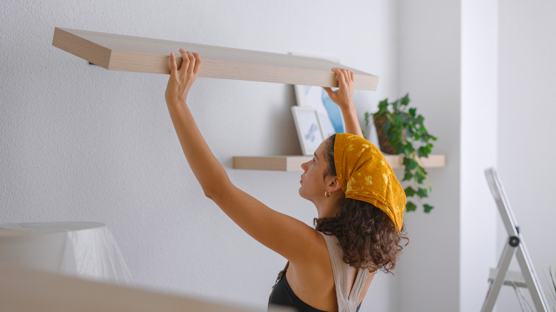 woman putting up shelves in home