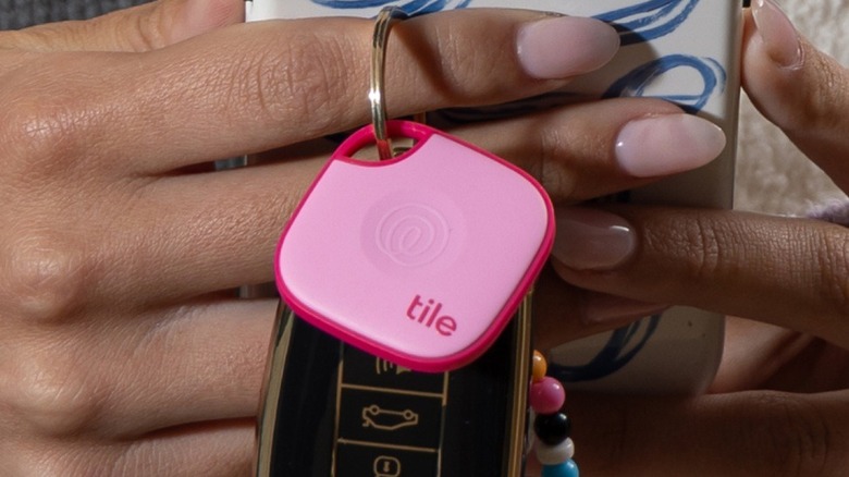 Pink Tile tracker attached to keys held in hand.