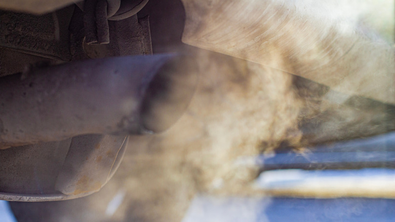 The exhaust of an idling car pumping smoke