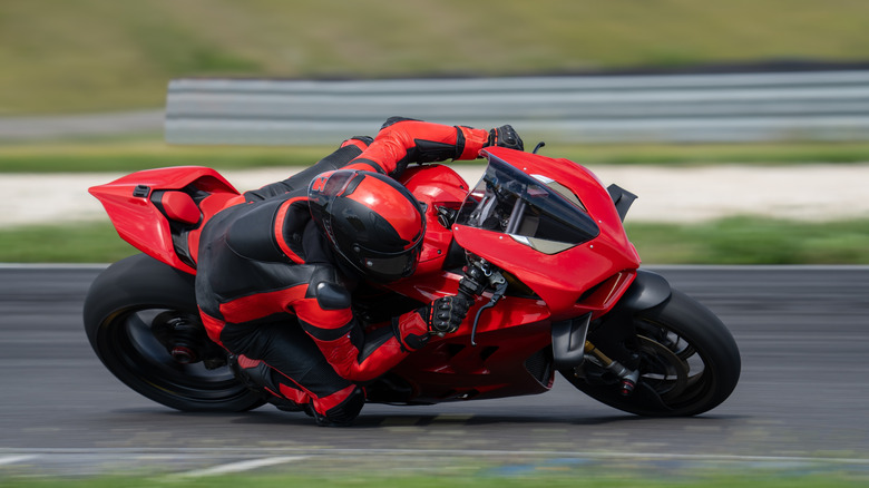 Motorcycle rider dragging knee through a corner on racing track.