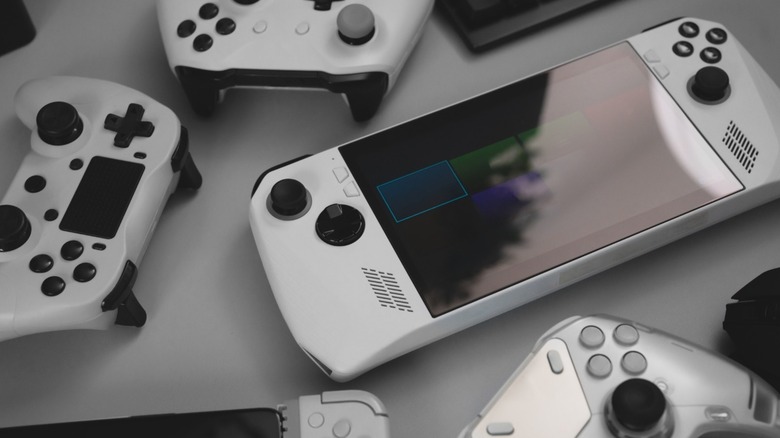 A handheld gaming console surrounded by gamepads.