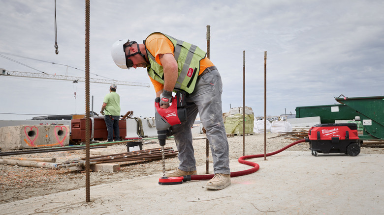 A worker using a Milwaukee rotary hammer on a jobsite.