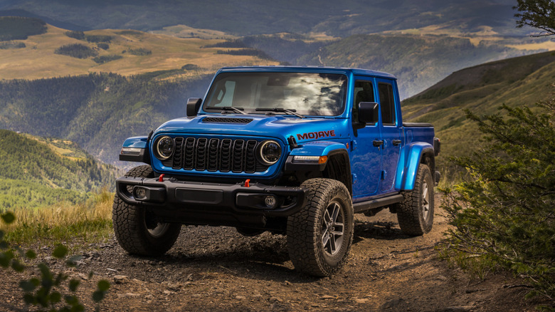 Blue 2025 Jeep Gladiator Mojave parked on a gravel road on a hillside