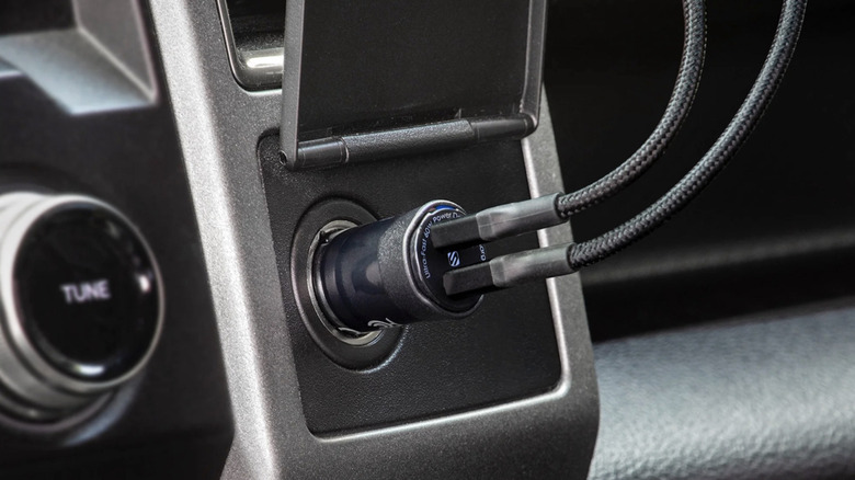 Scosche USB Car Charger plugged into a dashboard with two connected USB cables.