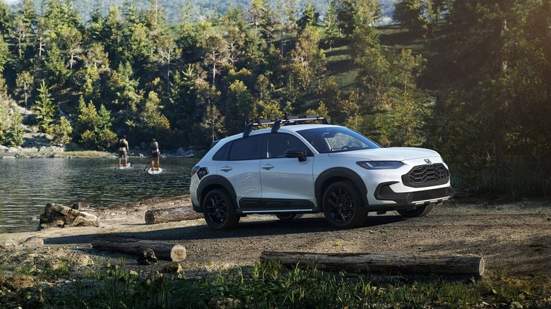 A white 2025 Honda HR-V parked beside a lake with paddleboarders on the water.