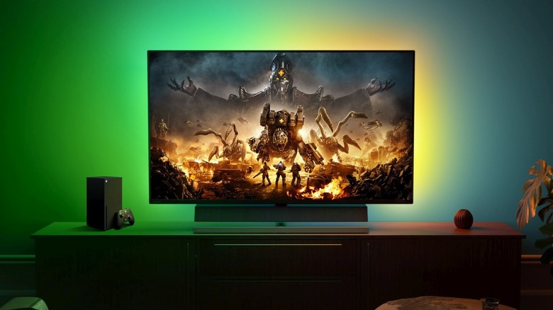 An Xbox Series X sits beside a TV showing a video game scene.