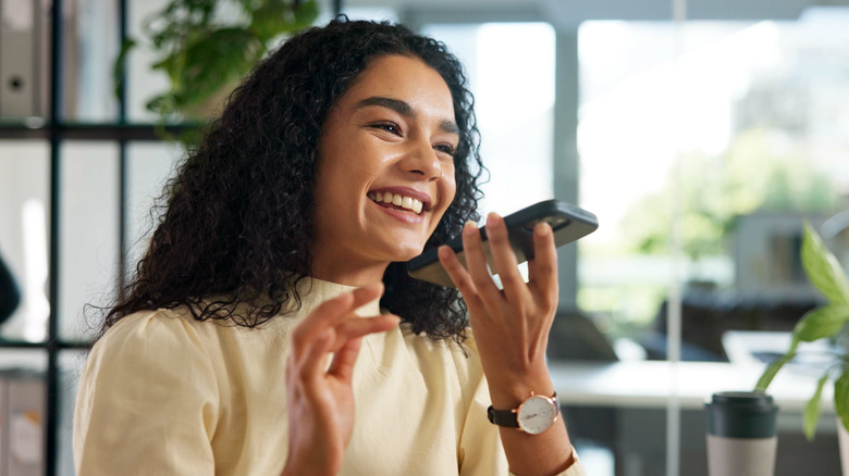 woman holding her phone up and speaking into it