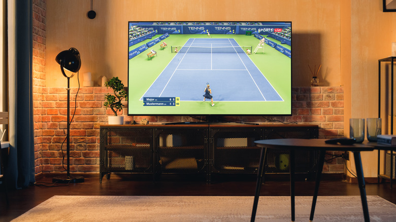 A TV mounted on a wall with a game of tennis playing on it