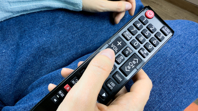 Closeup of a hand using a TV remote