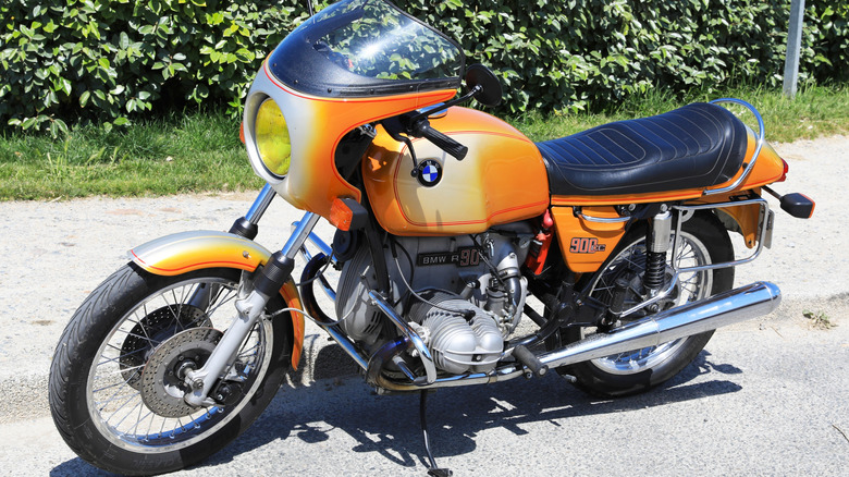 A classic yellow BMW R90S stood on its kickstand with racing fairing.