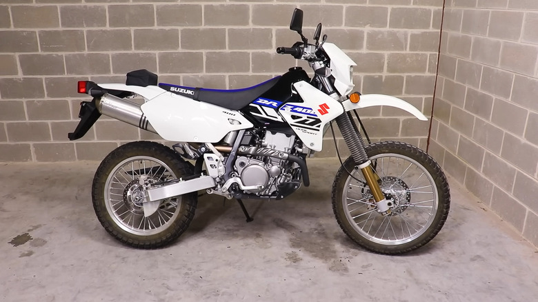 A white and blue Yamaha DRZ 400 propped up against a brick wall.