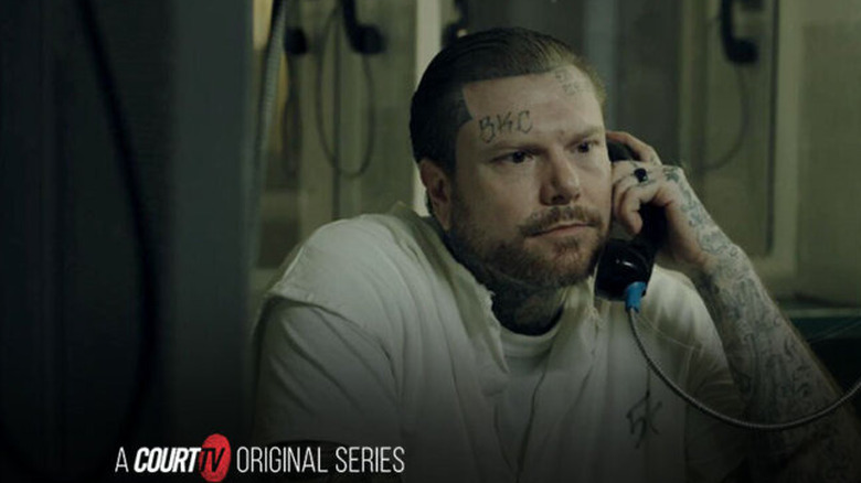 A man puts his ear onto a phone in prison.