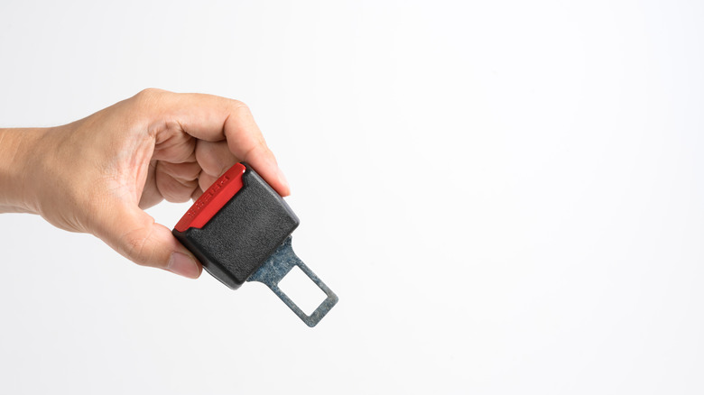 A hand holding a dummy belt buckle