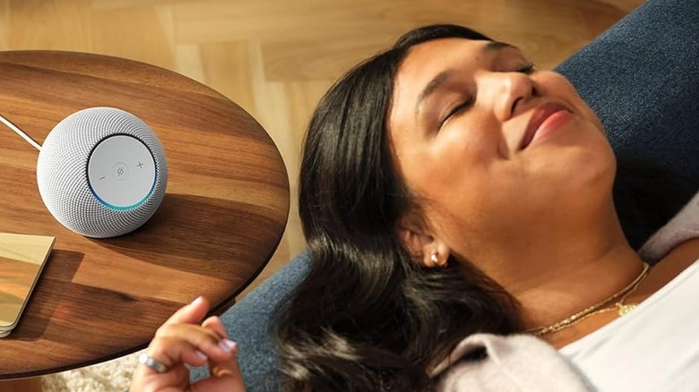 A woman relaxes as the Echo Dot Max sits on a table nearby.