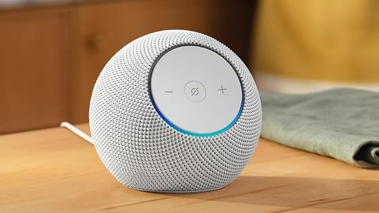 A woman walks near an Echo Dot Max sits on a table nearby.