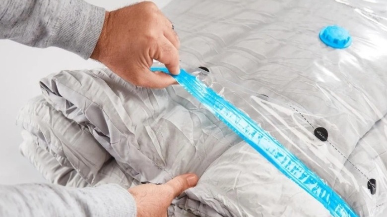 Pair of hands removing a blanket from a clear bag