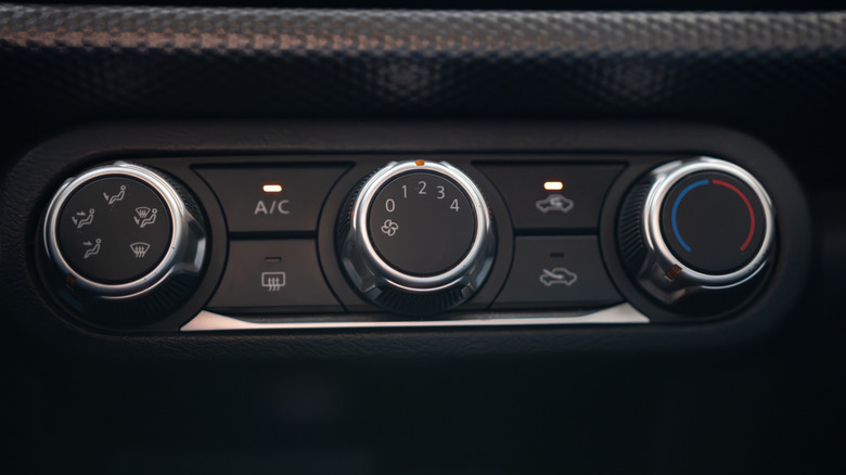 Three black and silver dials in a car that control the HVAC system