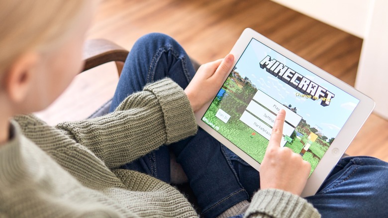 a girl playing Minecraft on an older tablet