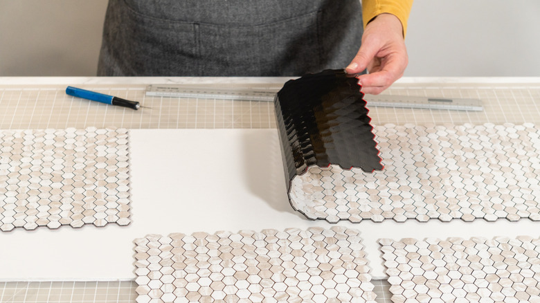 Person holding a sheet of stick-on tile