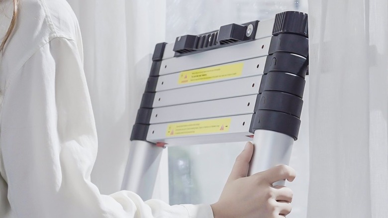 Woman holding Vevor 10.5 ft Telescoping Ladder