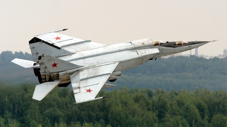 A MiG-25 fighter jet flying on a cloudy day