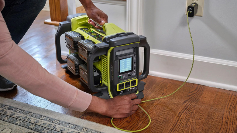 A person plugging in a Ryobi power station to the wall