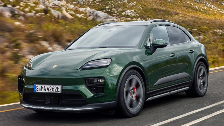 green Porsche Macan EV driving past rocky hillside