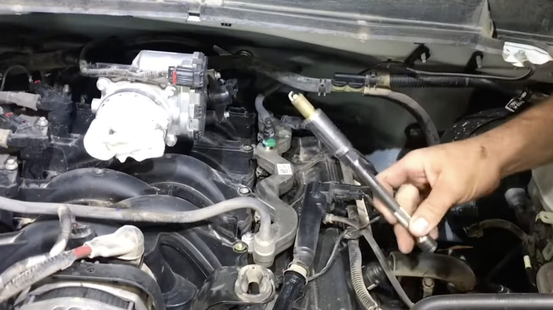 man holding spark plug above Ford Boss 6.2-liter engine