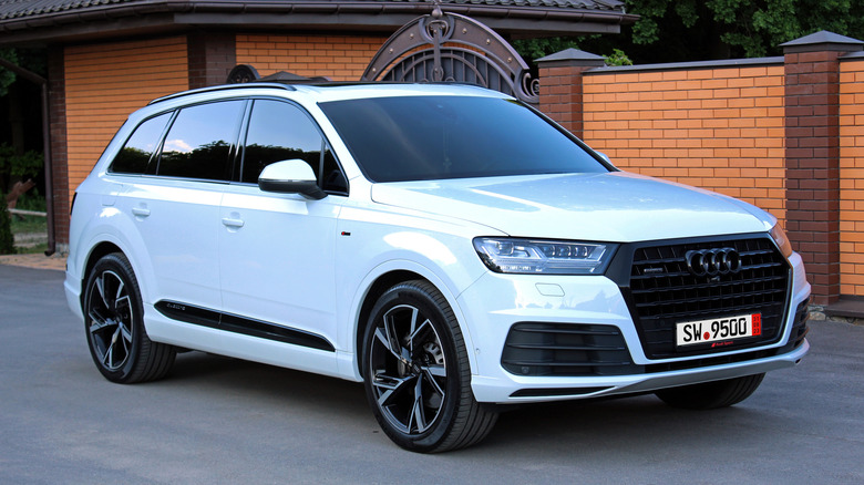 white audi Q7 parked in front of brick wall with gate