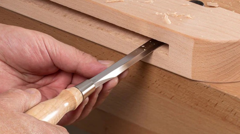 a person using a blue spruce toolworks bench chisel on a woodworking project