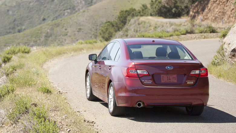 The rear view of 2015 Subaru Legacy on a mountain road.