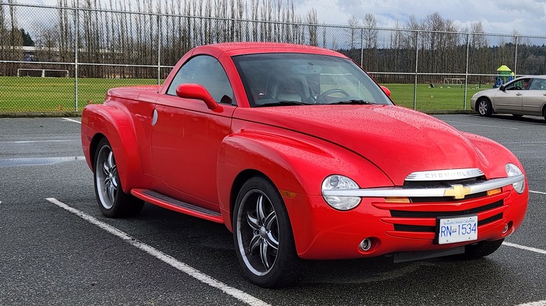 red Chevrolet SSR in an almost empty parking lot with soccer field in background
