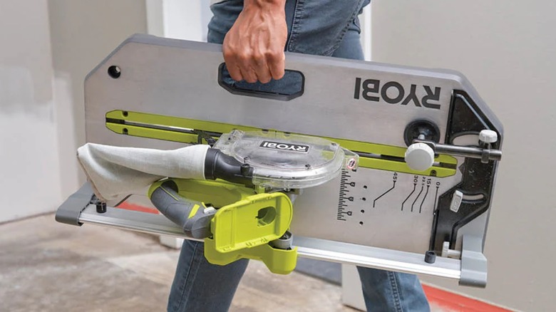 A person carring the Ryobi flooring saw by its handle