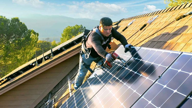 Person installing solar panels on a roof
