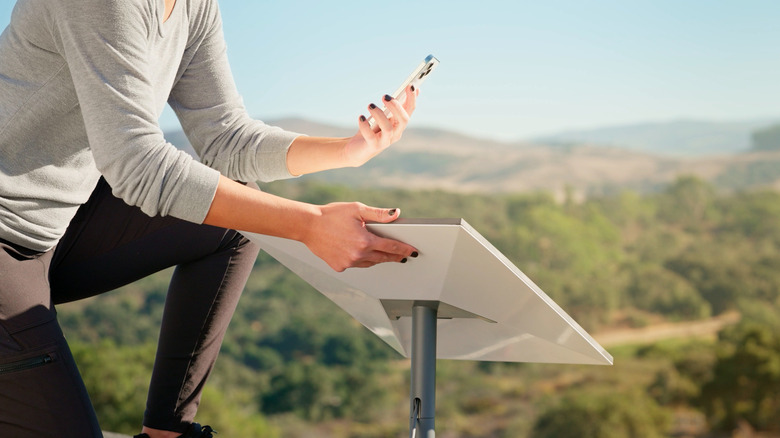 Woman positioning Starlink dish while looking at phone