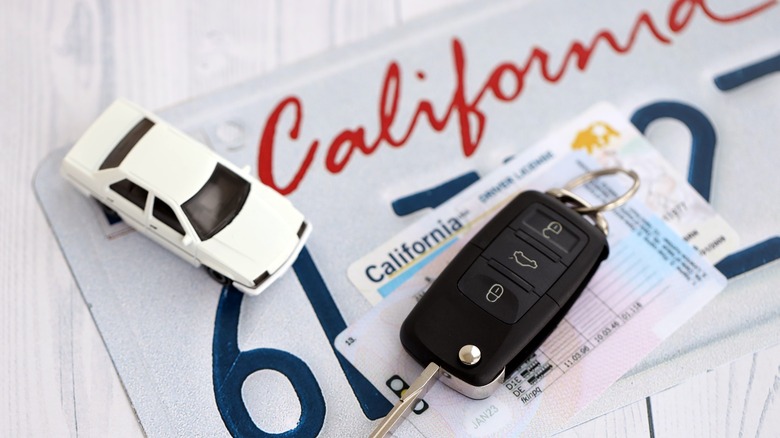 A California license plate with a key and other documents. on top of it