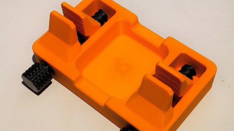 An orange and black 3D-printed solder cable holder.