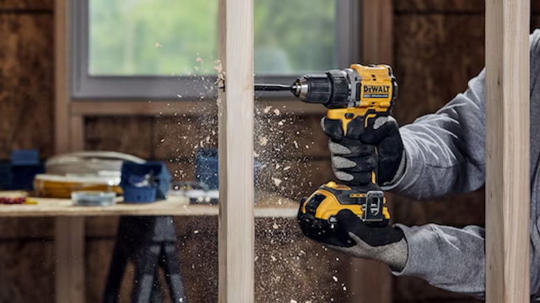 person using DeWalt Atomic 20V cordless drill/driver on a wood beam