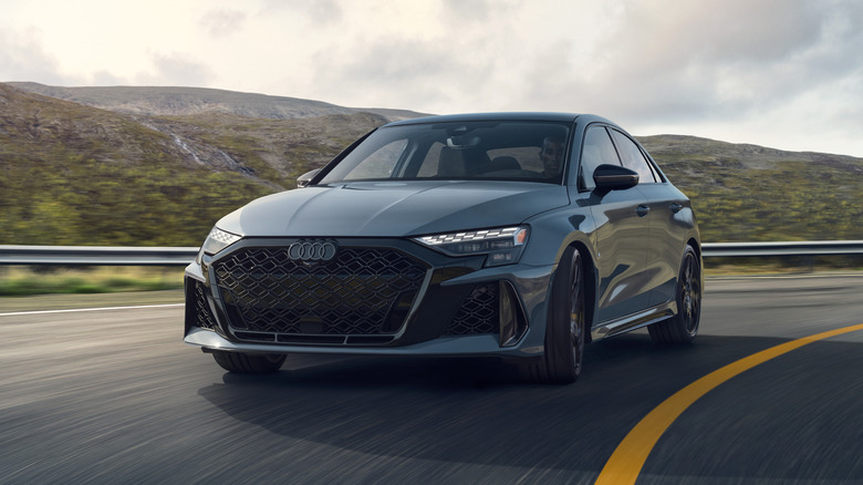 2025 Audi RS3 driving on a road with mountains in the background