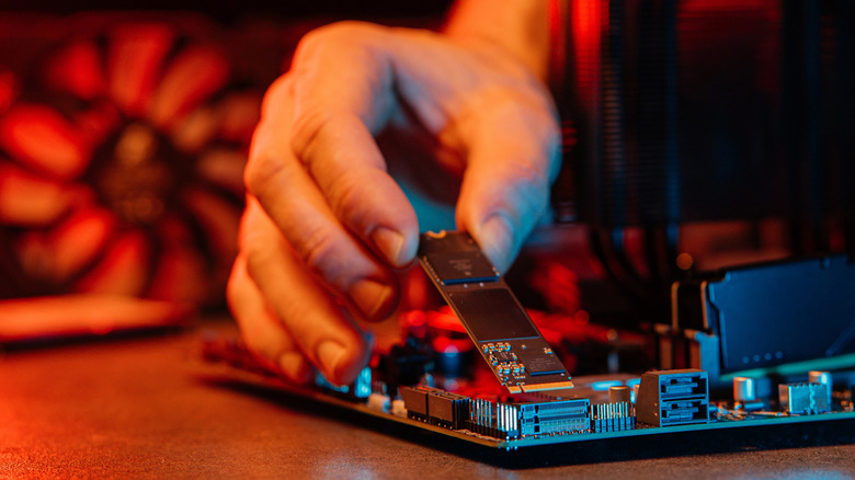 A person installing an NVMe drive into a motherboard
