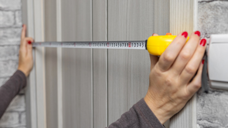 A person using a tape measure on a doorway.