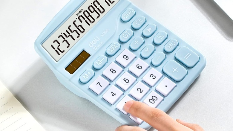 Finger touching blue Deli Standard Calculator on table