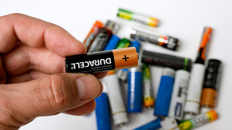 Hand holding Duracell AA battery with AA batteries in the background
