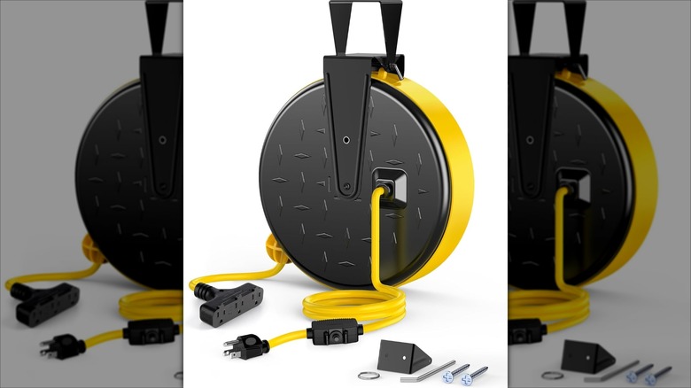 A yellow Retractable Extension Cord on a black hub. It has a handle, and there are accessories next to it.
