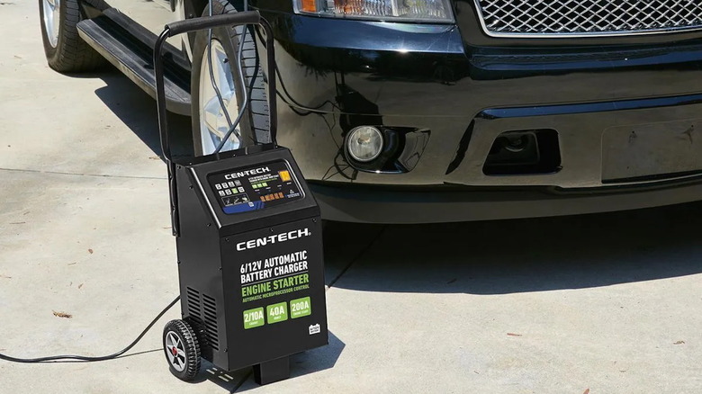 Cen-Tech 200 Amp, 6/12V Wheeled Automatic Battery Charger with Engine Jump Start in front of an SUV