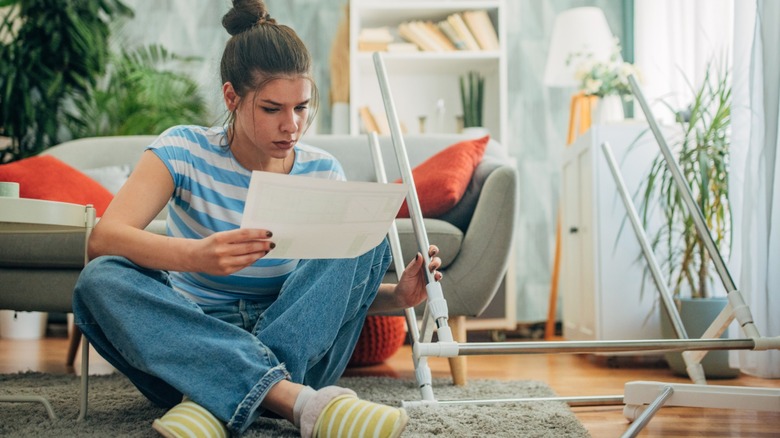 Woman reading instructions while assembling furniture