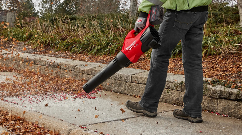man using a Milwaukee M18 FUEL leaf blower on sidewalk